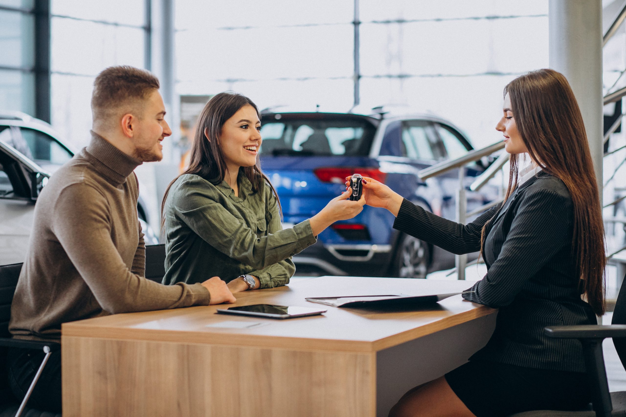 Young couple discussing car options with a salesperson in a showroom