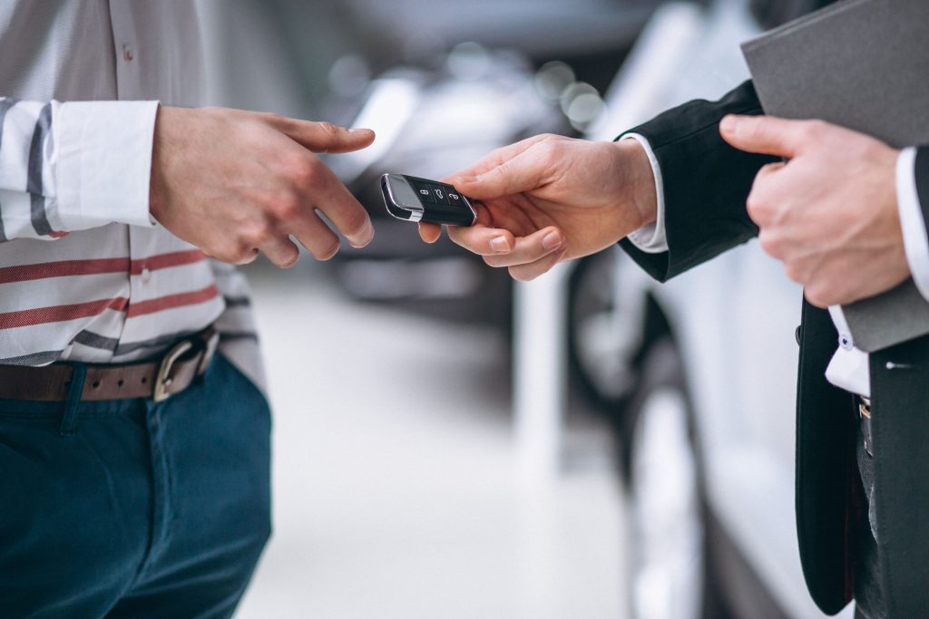 Two suited men with a car key, illustrating the importance of Texas Lemon Law protections for car buyers and lessees.