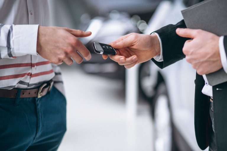Two suited men with a car key, illustrating the importance of Texas Lemon Law protections for car buyers and lessees.