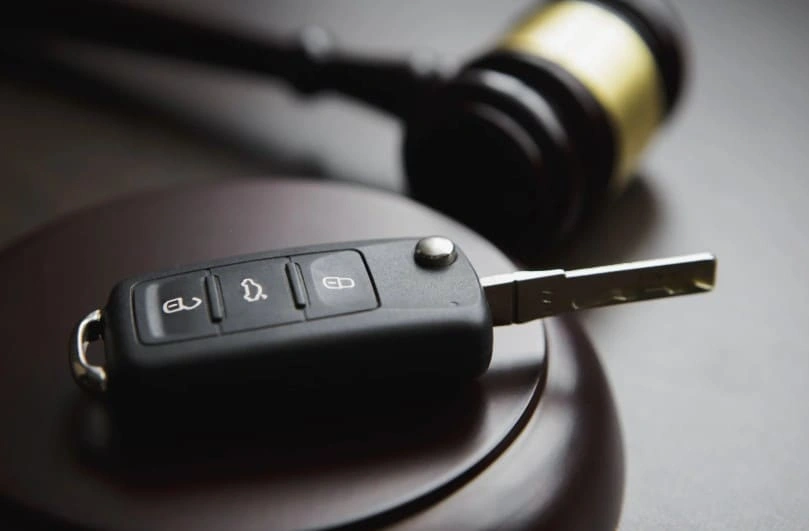 Car key fob resting on a judge's gavel, symbolizing consumer legal rights, vehicle defect claims, and lemon law protections for car owners.