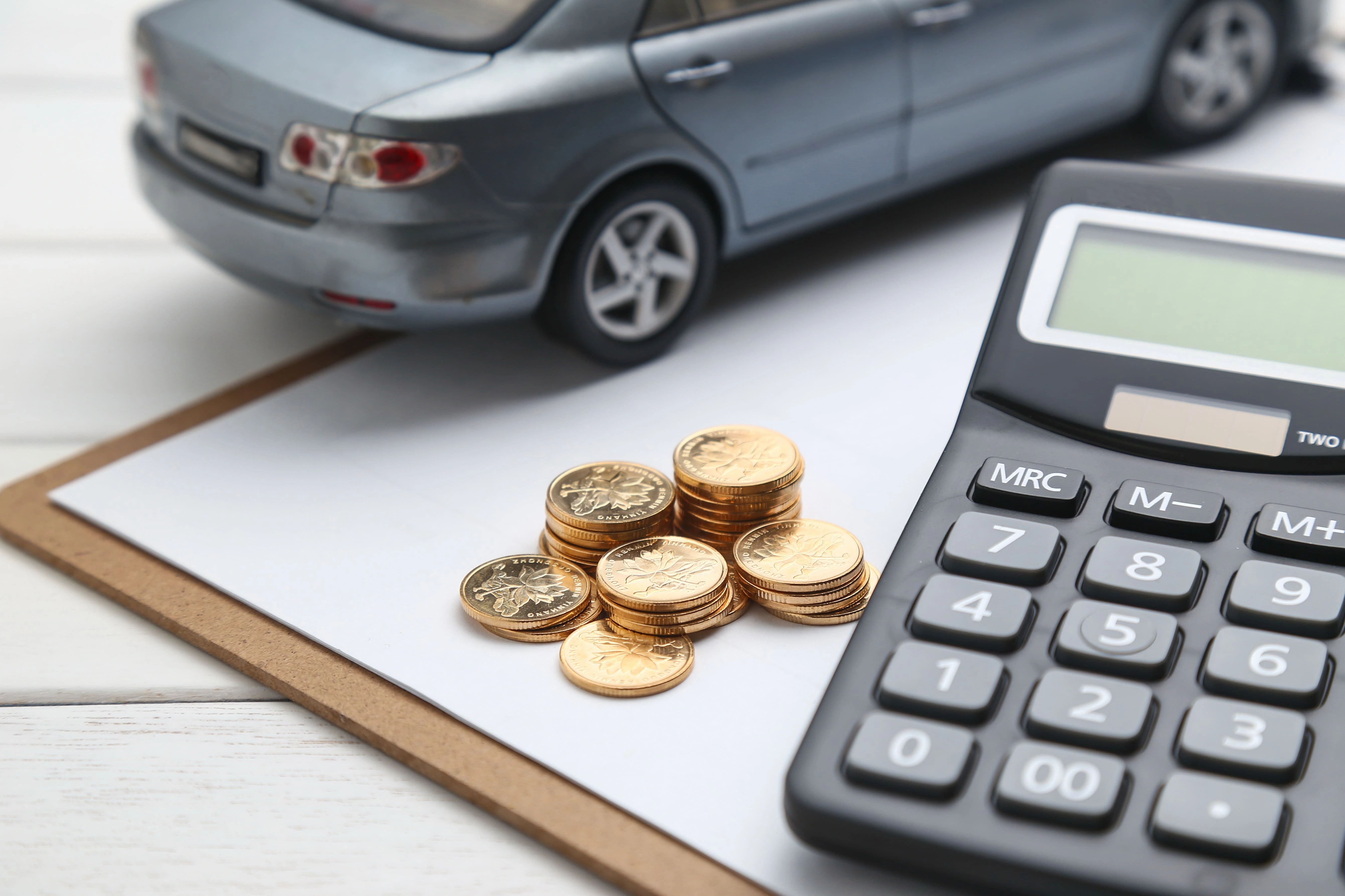 Calculator, coins, and a vehicle model representing lemon law buyback calculations, vehicle refunds, and compensation for defective cars.