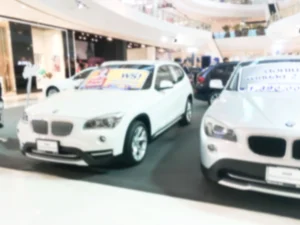 Row of used cars displayed at a dealership showroom with price signs, illustrating lemon law used car protections