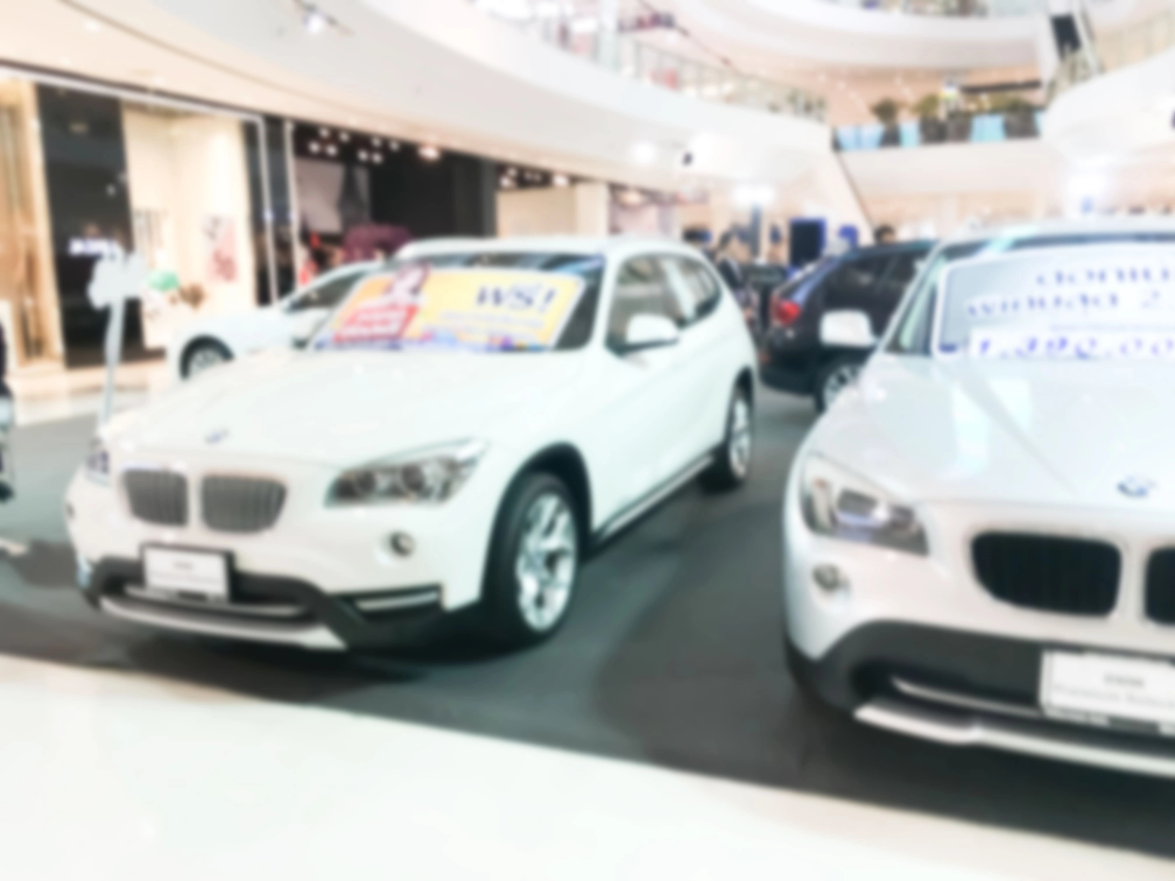 Row of used cars displayed at a dealership showroom with price signs, illustrating lemon law used car protections