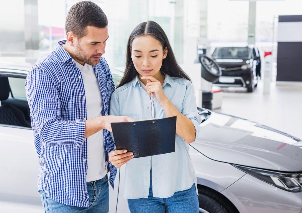 Couple standing together inside a showroom deciding on a car purchase