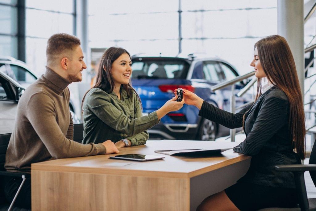 Young couple discussing car options with a salesperson in a showroom