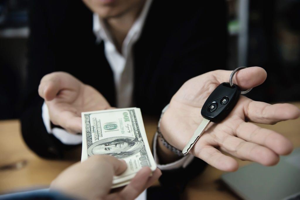 Two suited men with a car key, illustrating Florida Lemon Law refund and buyback rights.