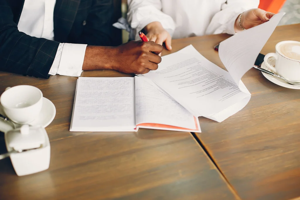 A man and woman sit at a table with papers and coffee, discussing the Arkansas Lemon Law claim process.