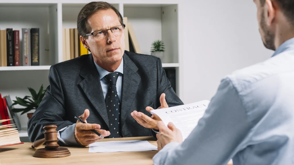 A man in a suit discusses legal matters with a lawyer regarding California Lemon Law protections for vehicle owners.